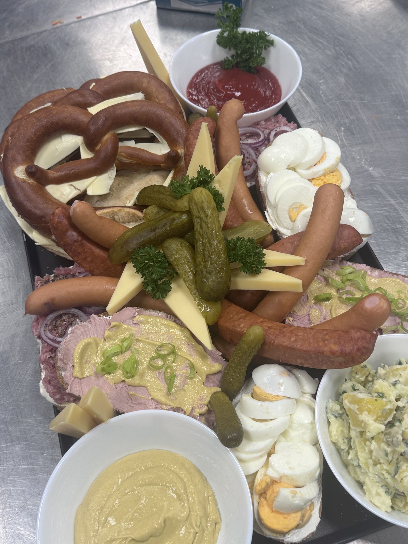 Deftiges Buffet mit Laugenbrezel, Würstchen, Käse und Kartoffelsalat