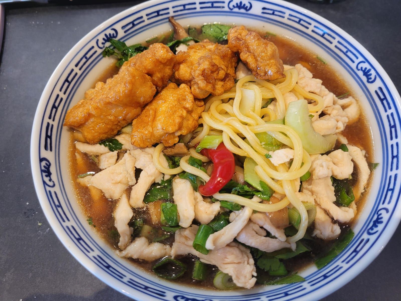 Asiatische Nudelsuppe mit knusprigem Backhendl, frischem Koriander und Chili