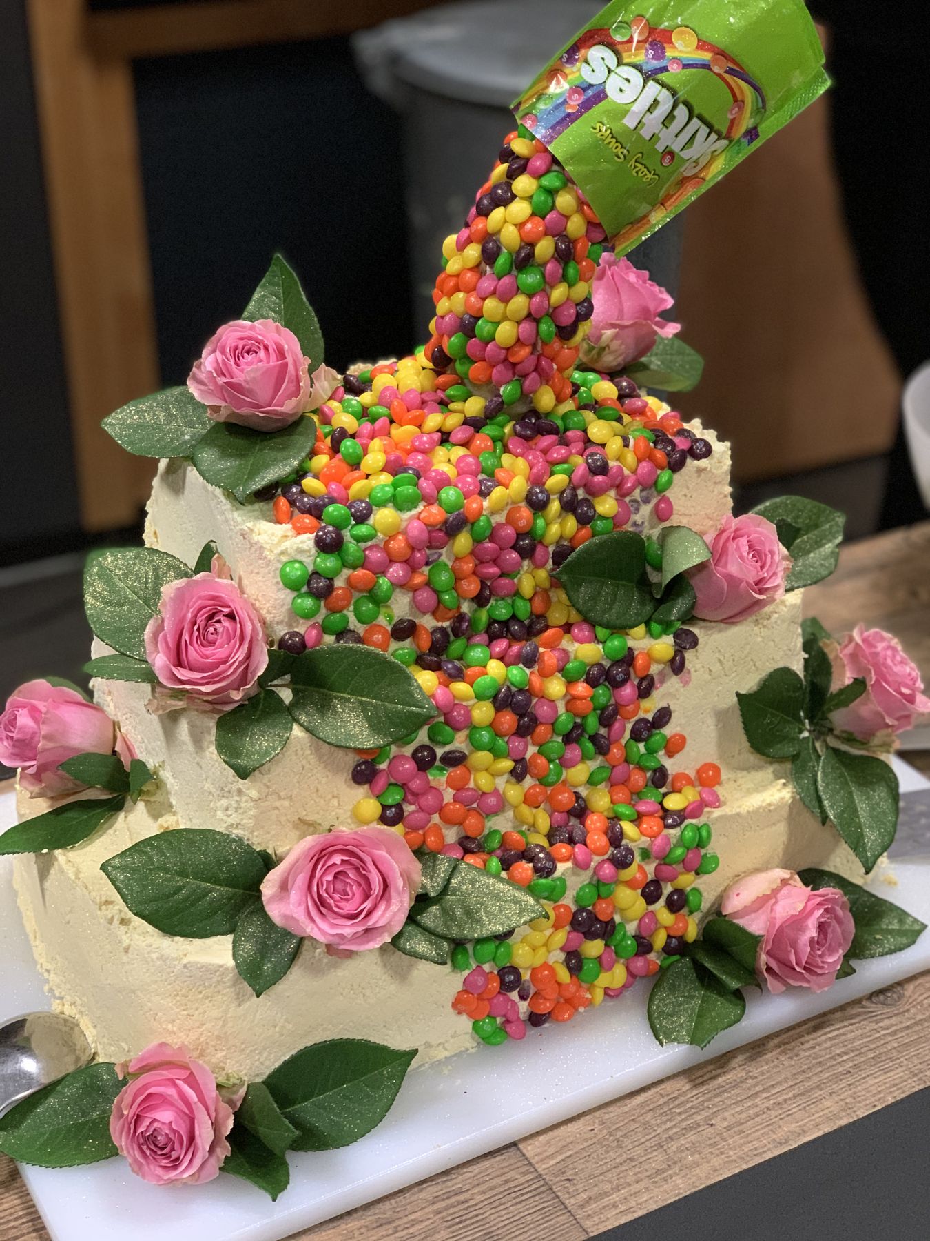 Bunte Regenbogen-Torte mit Rosen und Bonbons für Events